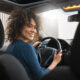 Mulher sorrindo enquanto dirige um carro