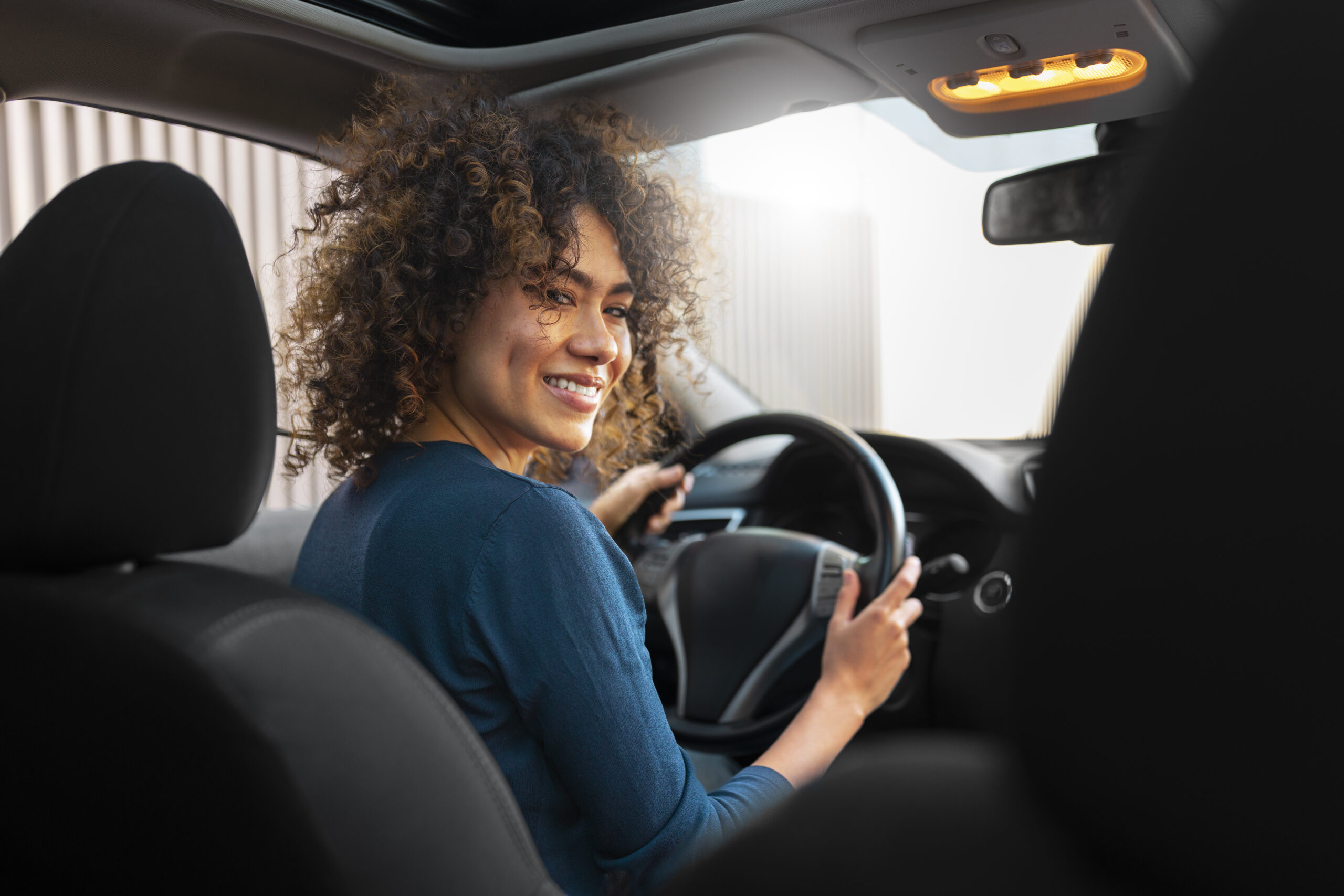 Mulher sorrindo enquanto dirige um carro