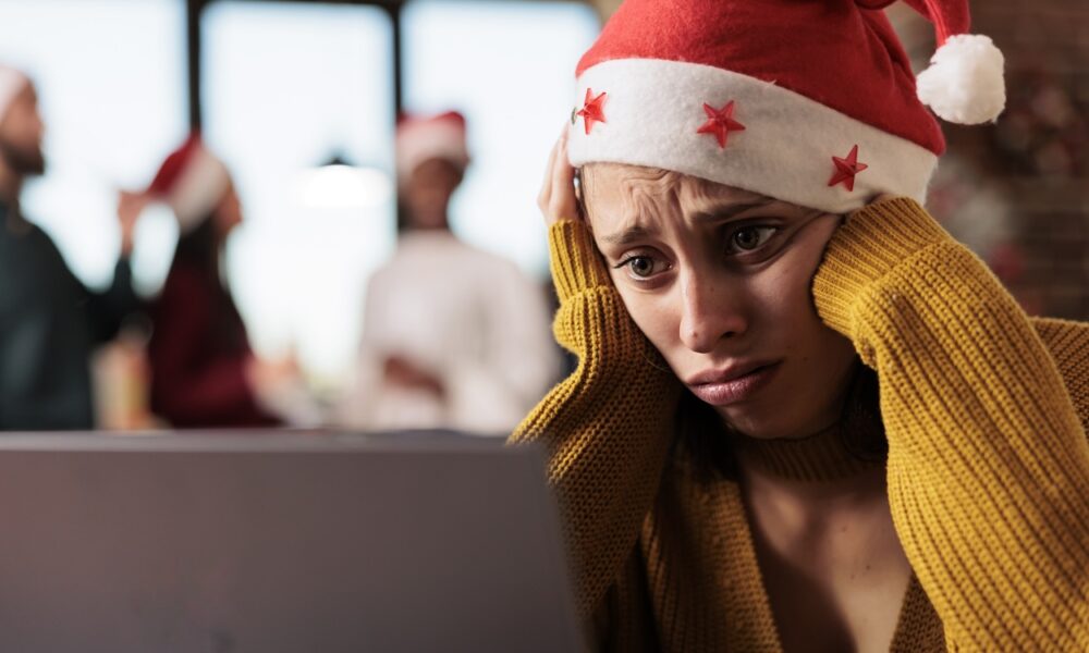 Mulher triste com gorro de natal olhando para notebook