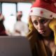 Mulher triste com gorro de natal olhando para notebook