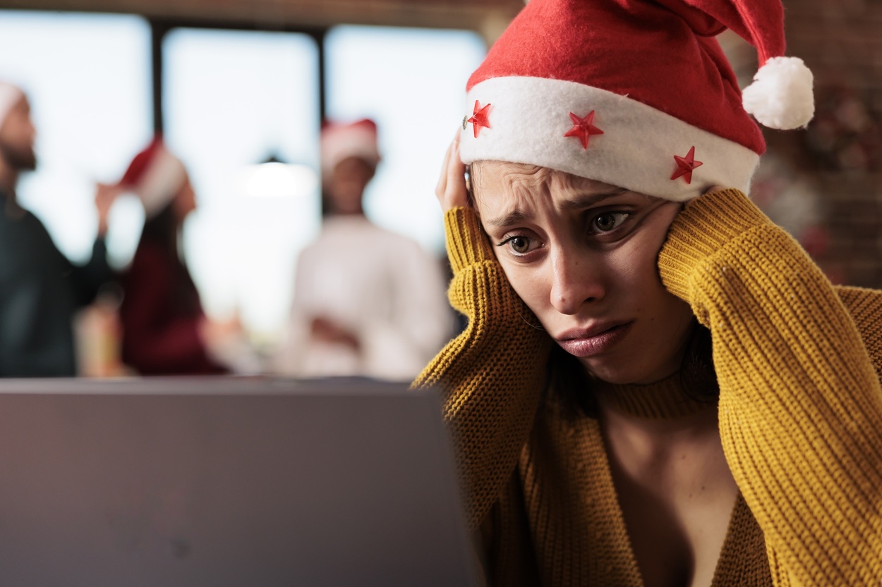 Mulher triste com gorro de natal olhando para notebook