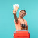 Homem com mala de viagem segurando passagens