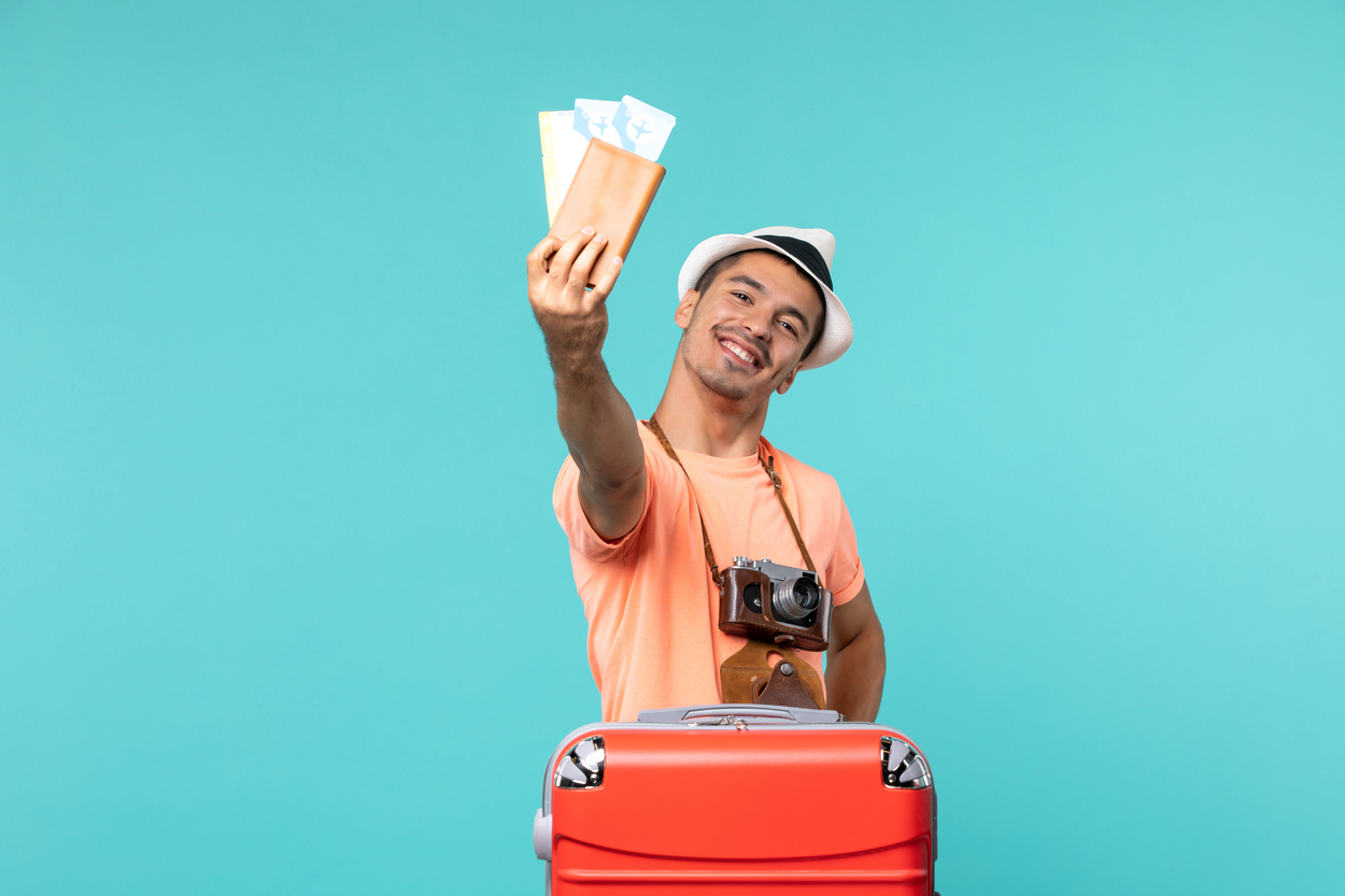 Homem com mala de viagem segurando passagens