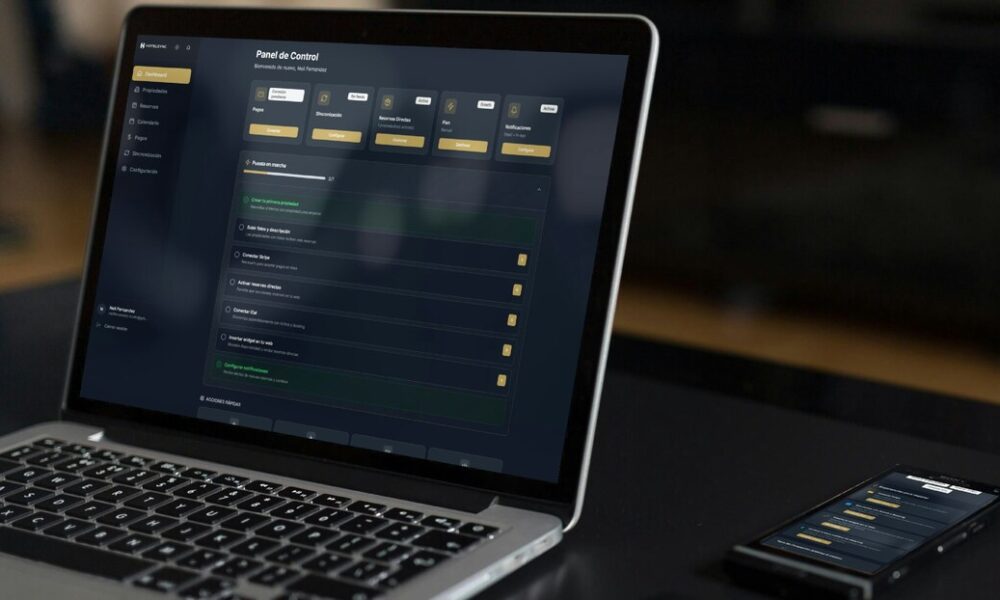Notebook e smartphones sobre uma mesa; ambos estão conectados no mesmo website, mostrando um dashboard de informações.