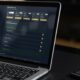 Notebook e smartphones sobre uma mesa; ambos estão conectados no mesmo website, mostrando um dashboard de informações.